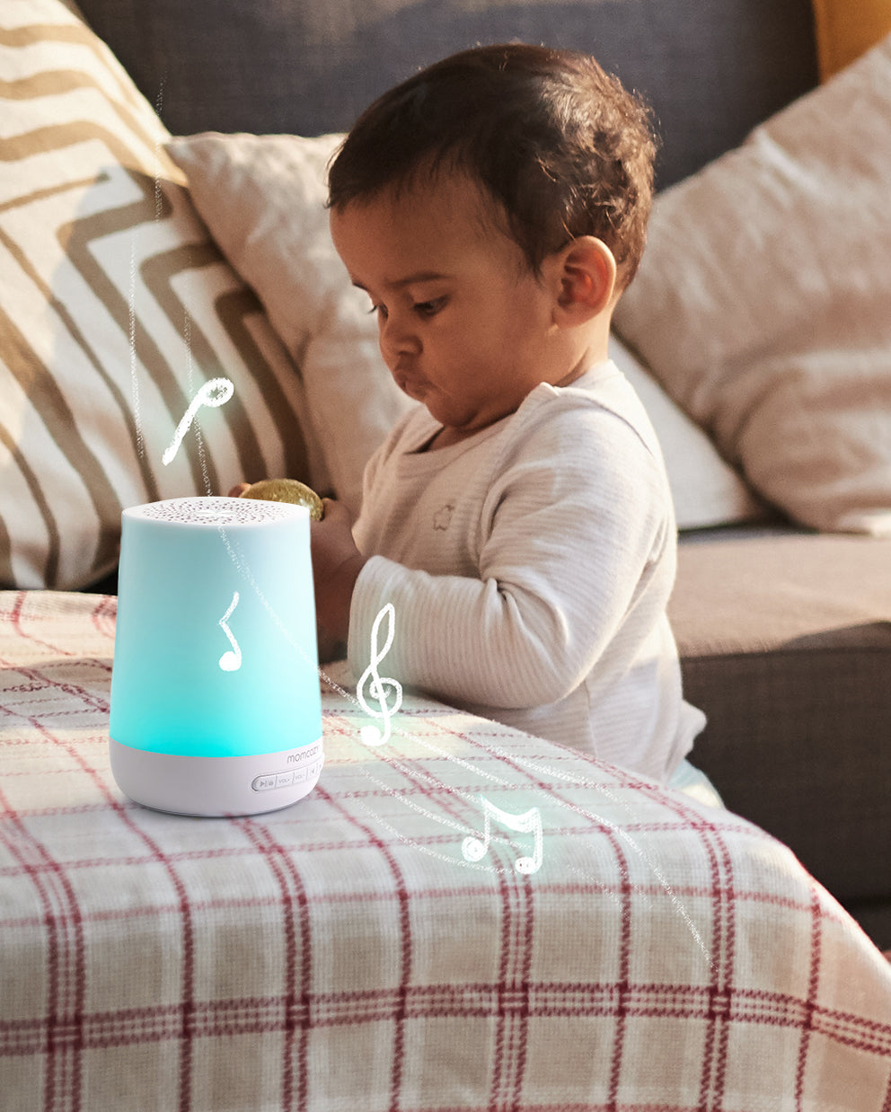 Baby interacting with smart sound machine, glowing blue with soothing music notes.